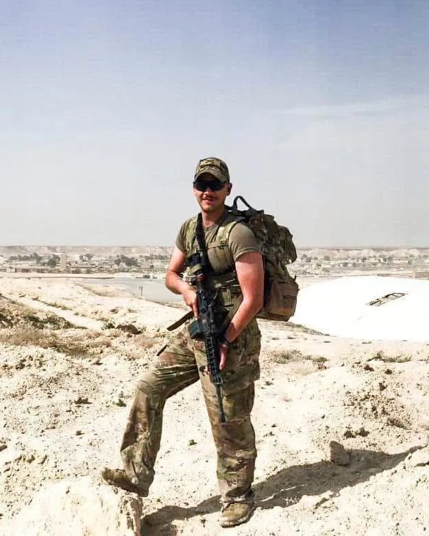 Alex smiling on a desert overlook, wearing a backpack